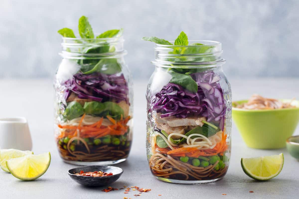 A healthy Asian themed cuisine using salads and noodles inside a mason jar