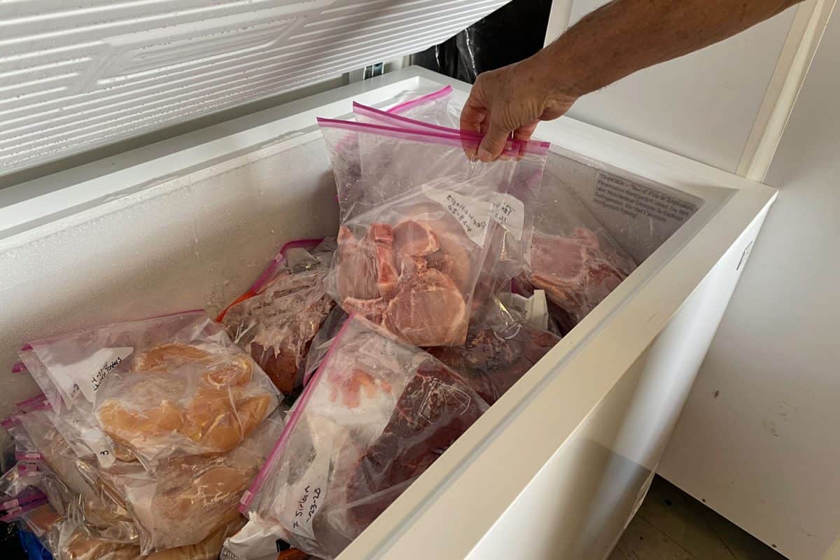 A man picking up packed meat in the chest freezer