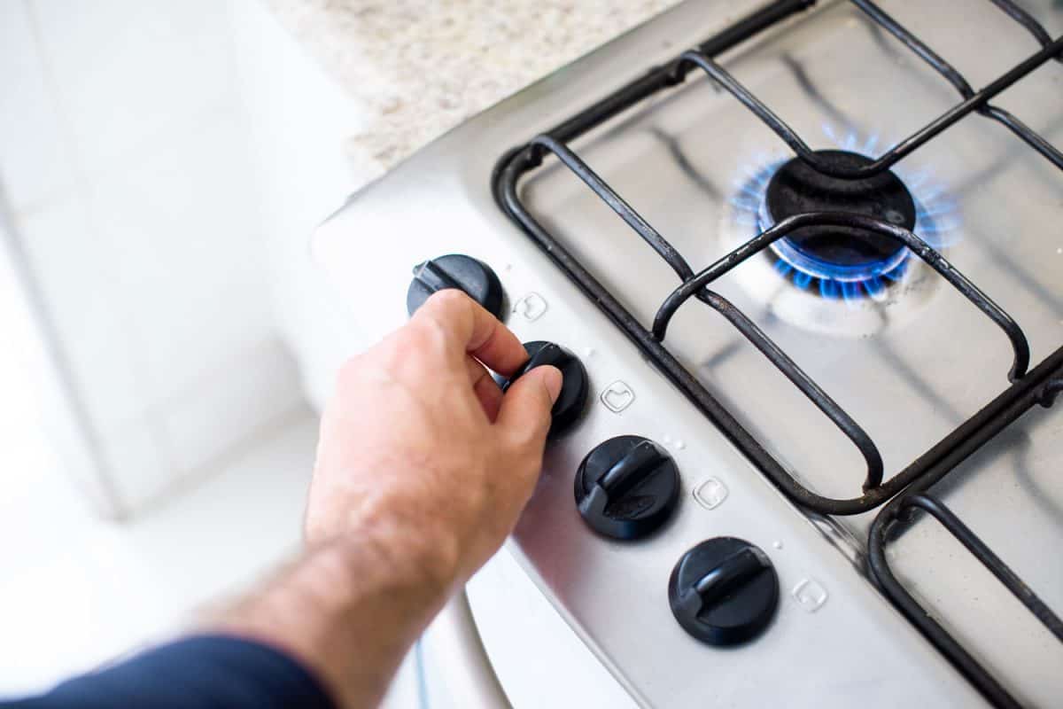 A man turning on the gas stove for cooking dinner