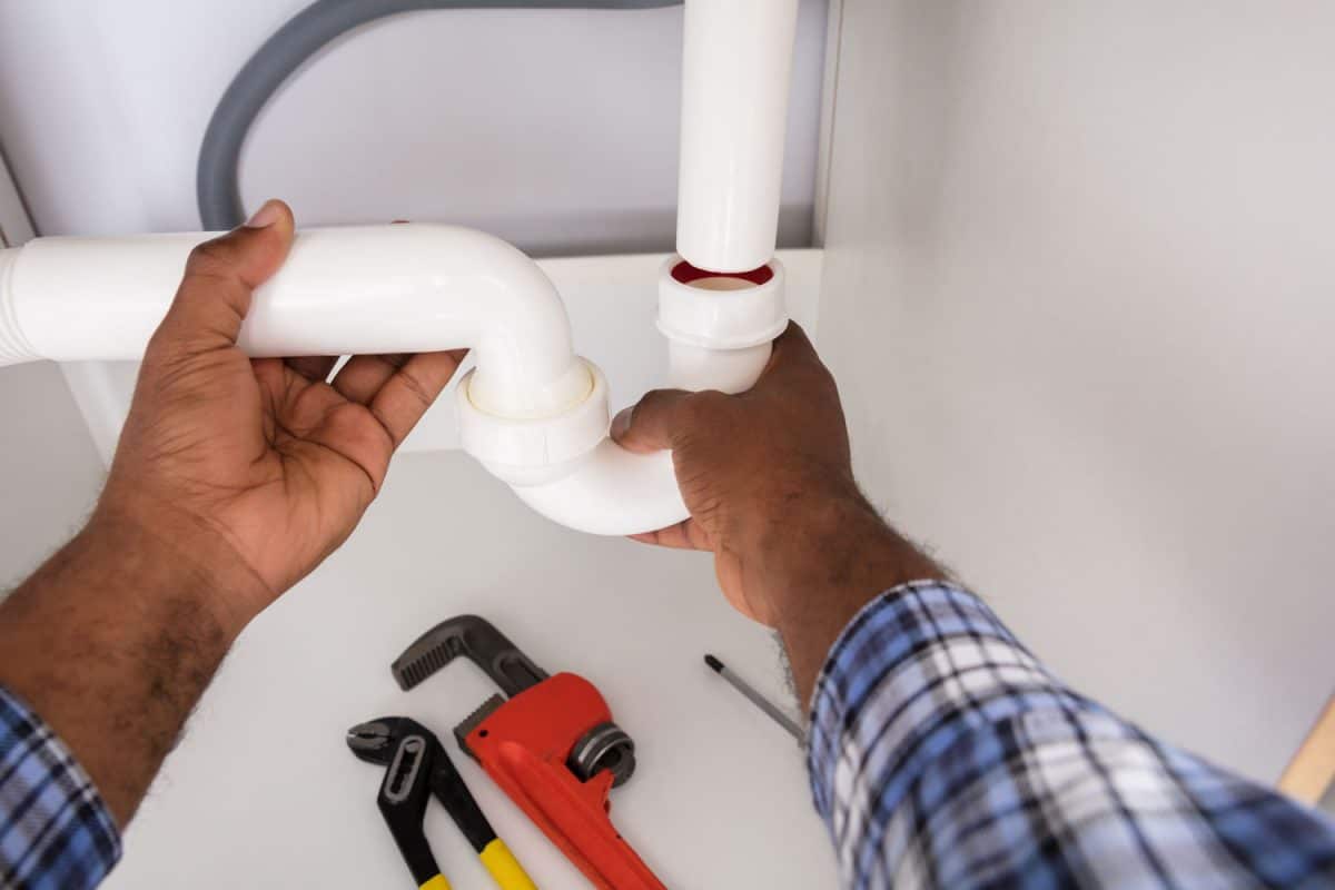 A plumber installing a P-trap under the sink