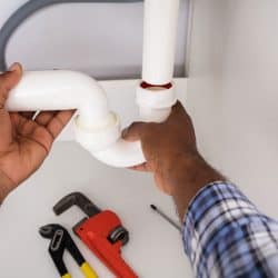 A plumber installing a P-trap under the sink, Does A Garbage Disposal Need A P-Trap?