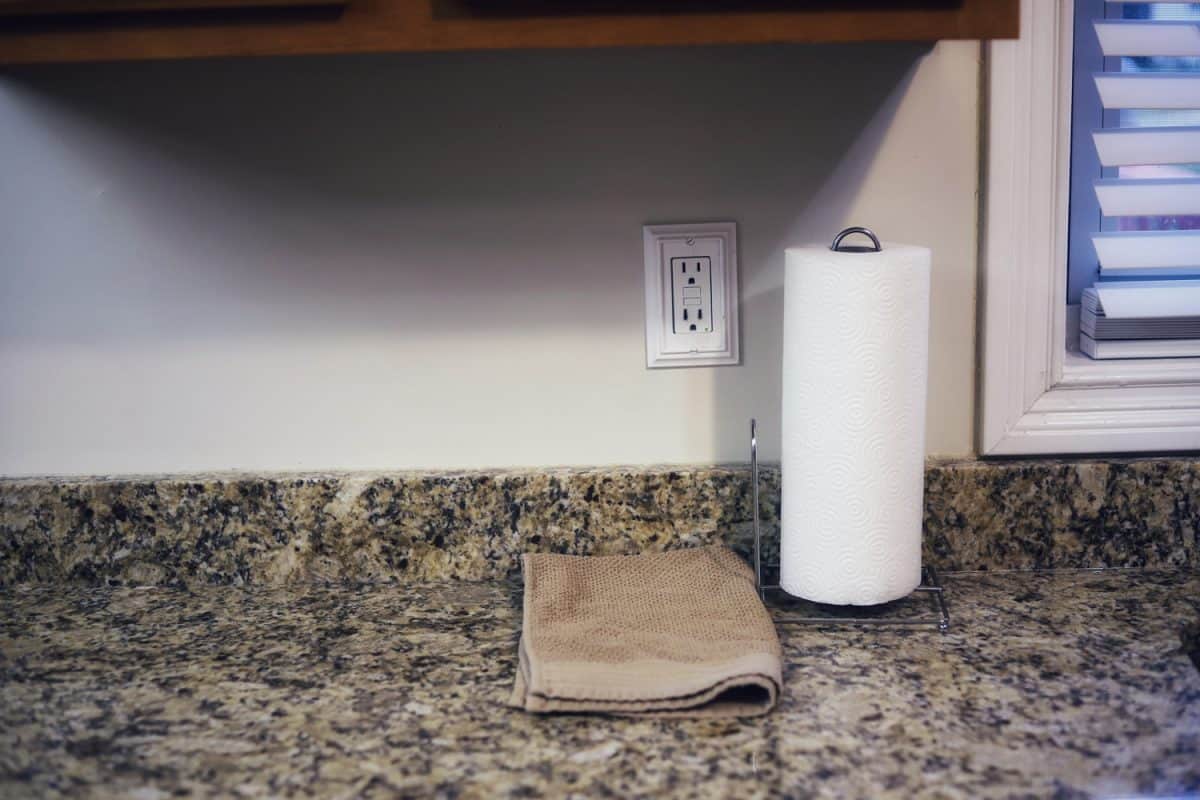 A roll of towel paper and a dish towel on a granite kitchen counter