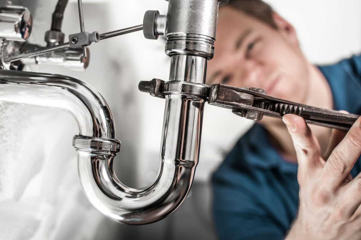 A selective focus photo of a plumber installing a P-trap