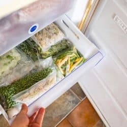 A woman checking the freezer drawer filled with vegetables, How To Repair A Cracked Freezer Drawer