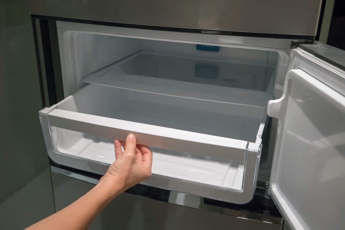 A woman opening the freezer drawer to clean it