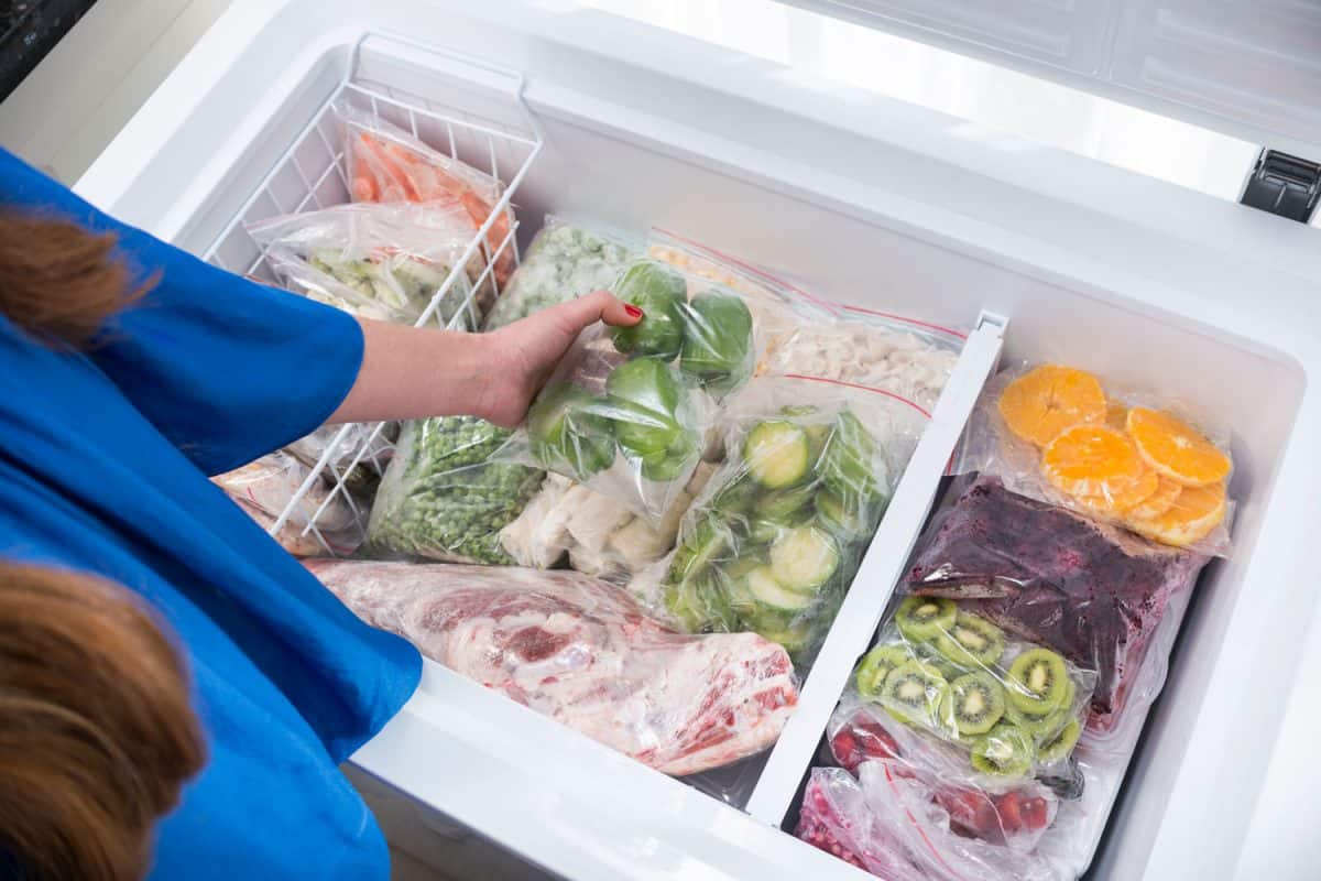 A woman picking out vegetables in her deep freezer