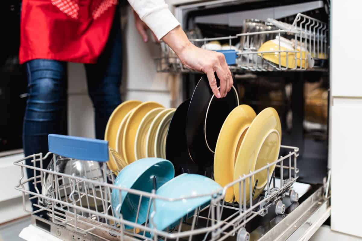 A woman putting dishes in the dishwasher for washing