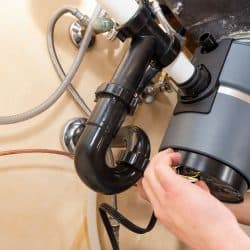 A worker checking the garbage disposal sink mechanism, How To Reset A Garbage Disposal In 4 Steps