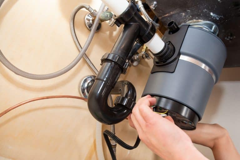 A worker checking the garbage disposal sink mechanism, How To Reset A Garbage Disposal In 4 Steps