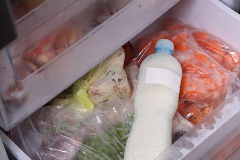 An opened chest freezer containing lots of vegetables and milk, Ice Buildup In Chest Freezer—What To Do?