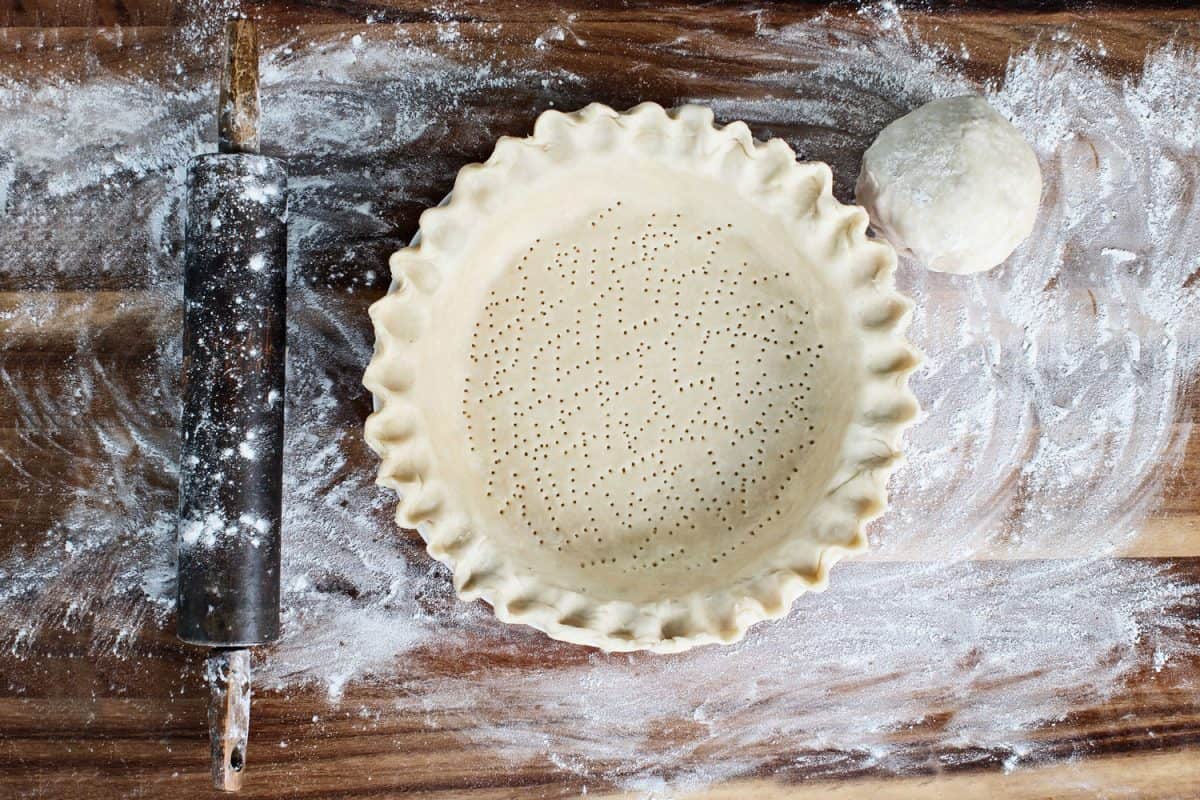An uncooked pie crust sprinkled with dough