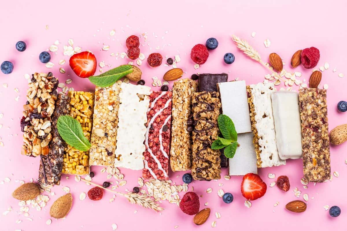 Assortment of different granola cereal bars on pink background