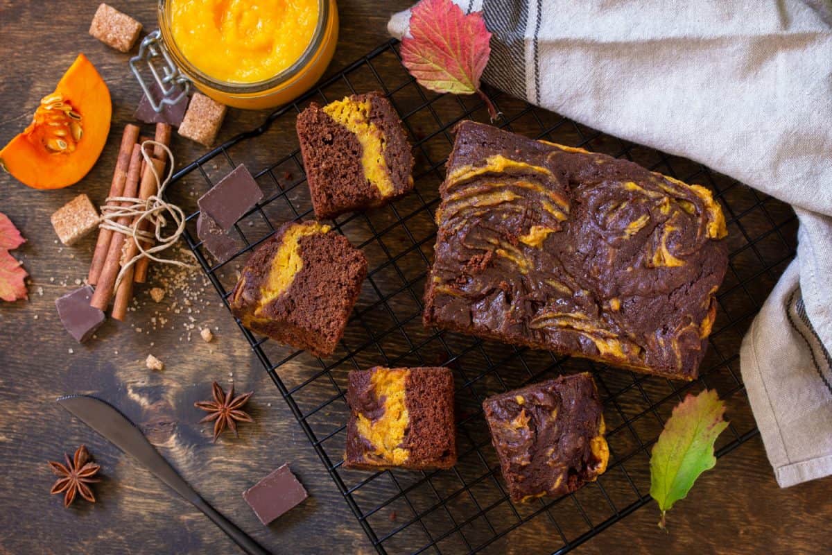 Baking Thanksgiving Day. Homemade chocolate brownie cake dessert with pumpkin puree and spices on a rustic wooden background. Top view flat lay background.
