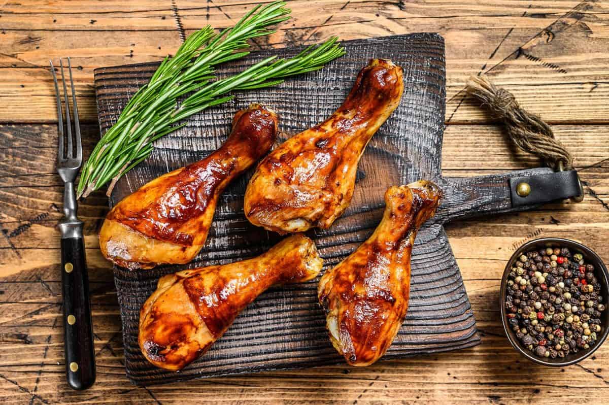 Barbecue roasted chicken drumsticks on a wooden cutting board