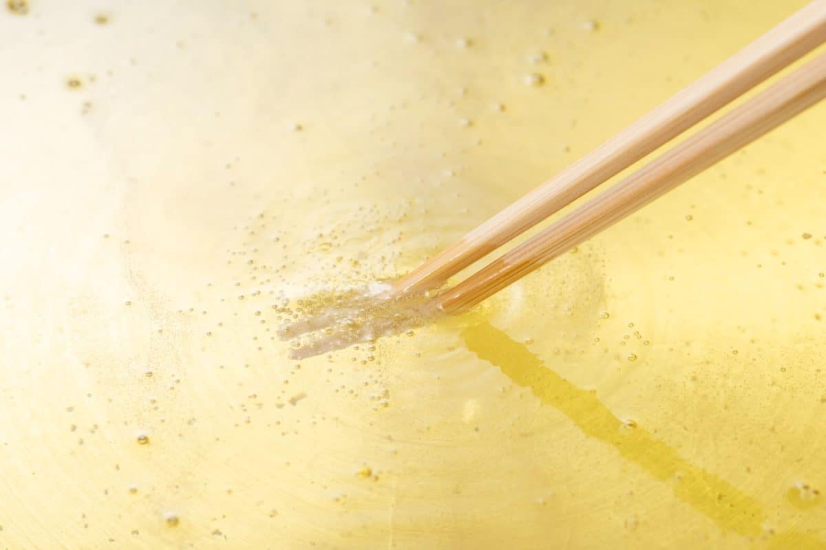 Dipping chopsticks to check the temperature of the oil