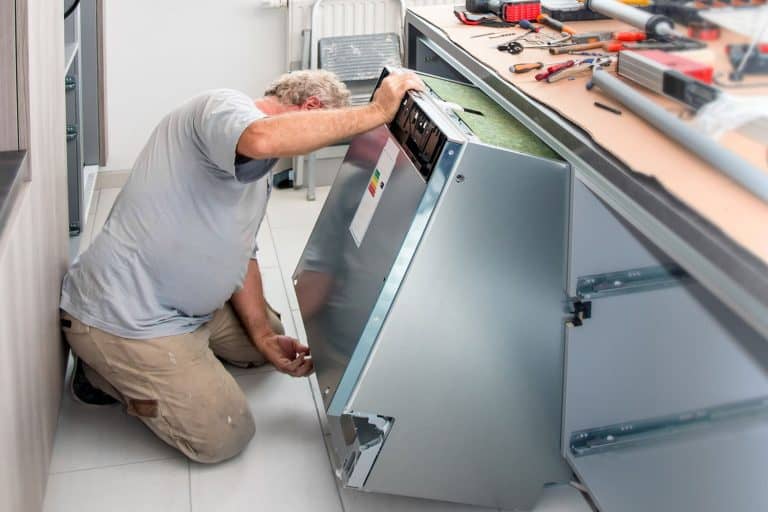 Fitter men manual worker installing new dishwasher appliance in kitchen, How To Install A Countertop Dishwasher Permanently