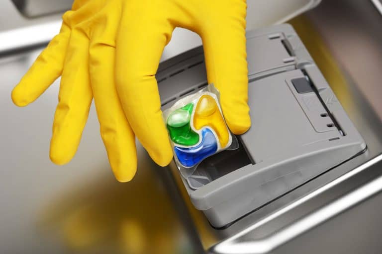 Hand putting detergent tablet into dishwater, Dishwasher Soap Dispenser Broken—What To Do?