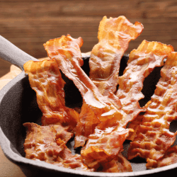 Hot fried bacon pieces in a cast iron skillet. What's The Best Type Of Pan For Cooking Bacon