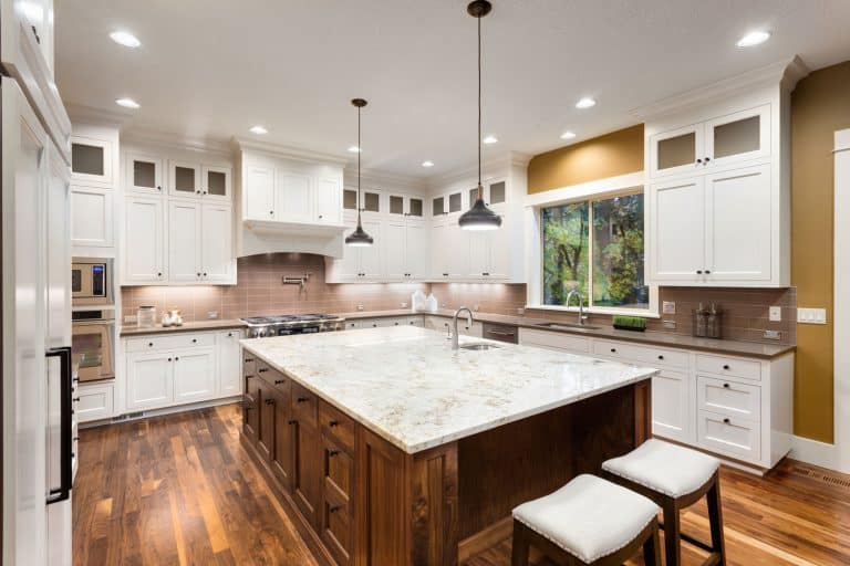 Large Kitchen Interior with Island, Sink, White Cabinets, Pendant Lights, and Hardwood Floors in New Luxury Home, How High Should Kitchen Counters Be?