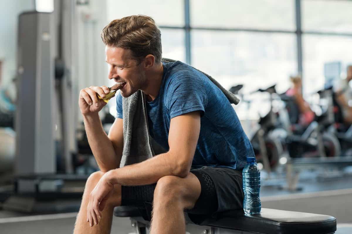 Man eating energy bar in the gym