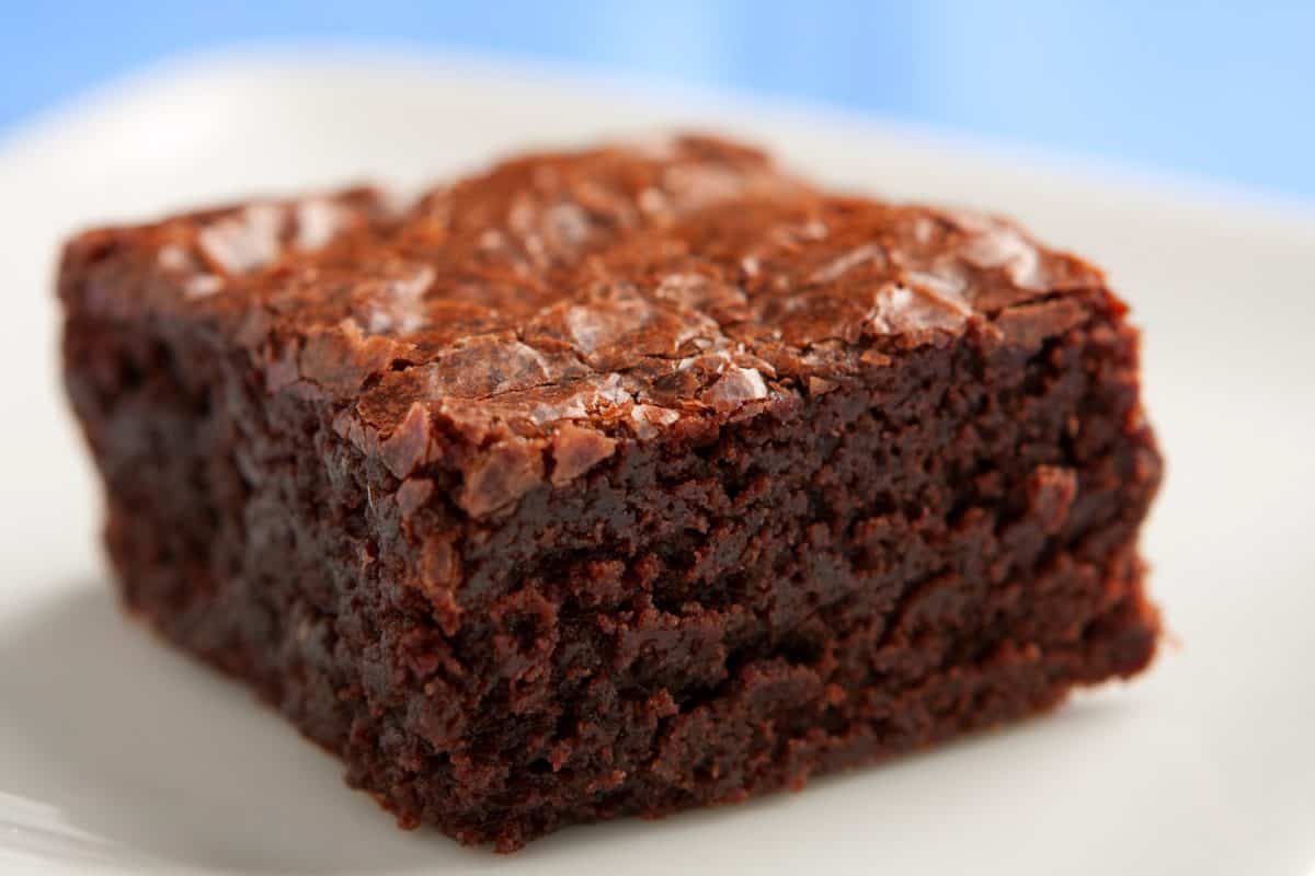 One freshly baked chocolate brownie on a plate.