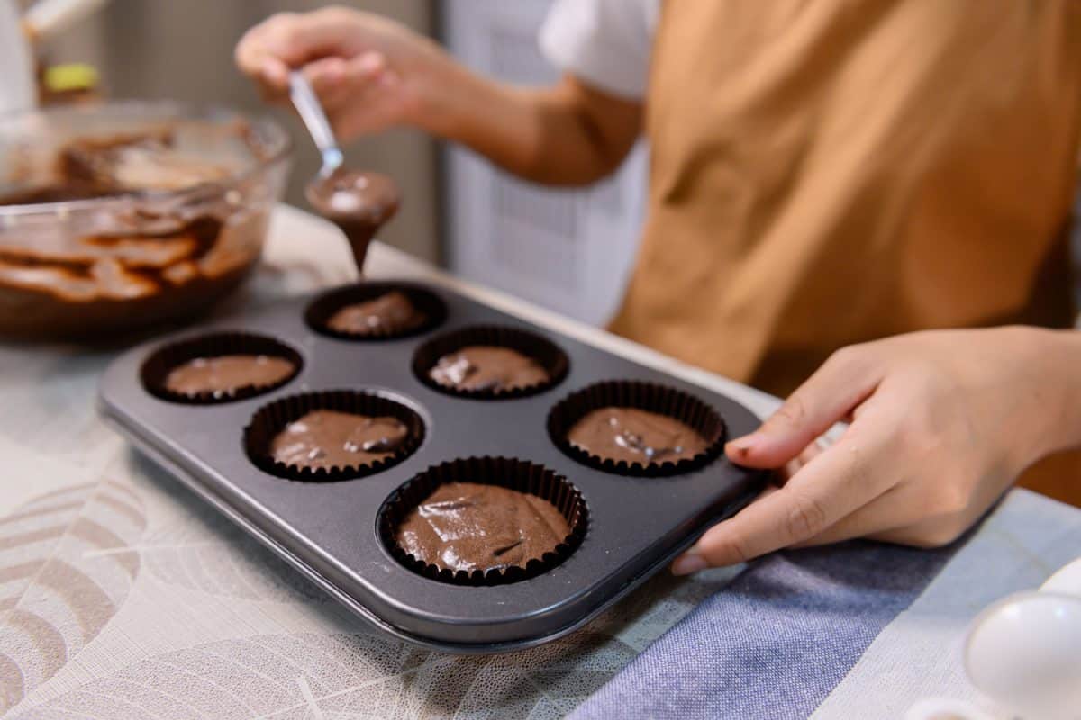 Process of cooking delicious homemade muffin and Halloween cupcake. Woman preparing and mixing ingredients for sweet food dessert in kitchen at home, Can Muffin Pans Go In The Dishwasher?