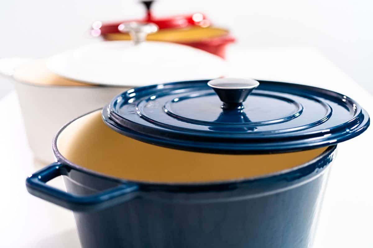Red, white and blue enameled cast iron covered round dutch ovens on a white background