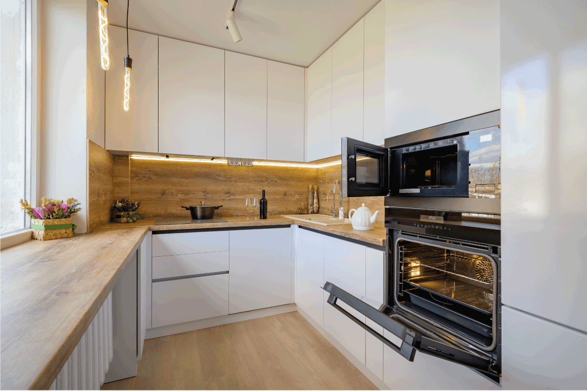 Well designed white and wooden beige modern kitchen interior with oven door opened. Should You Leave The Oven Door Open After Baking