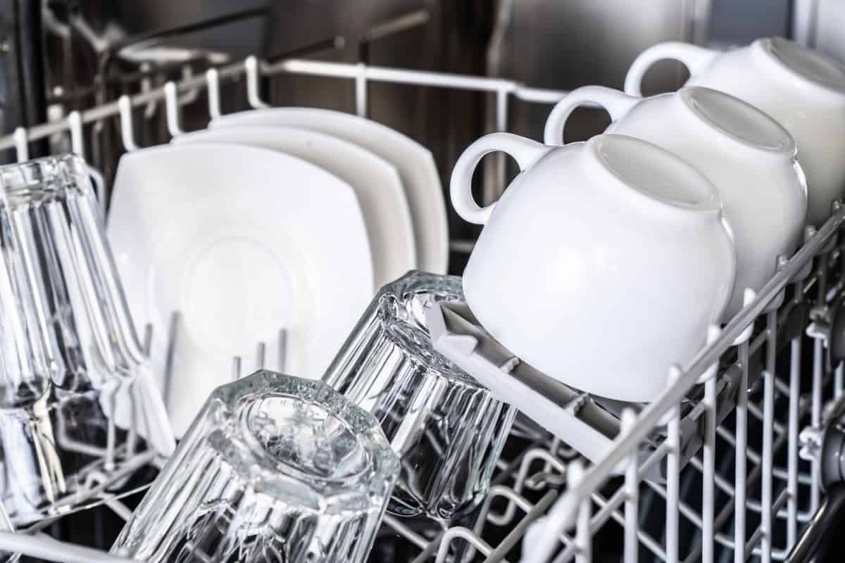 White ceramic mugs and plates inside the dishwasher