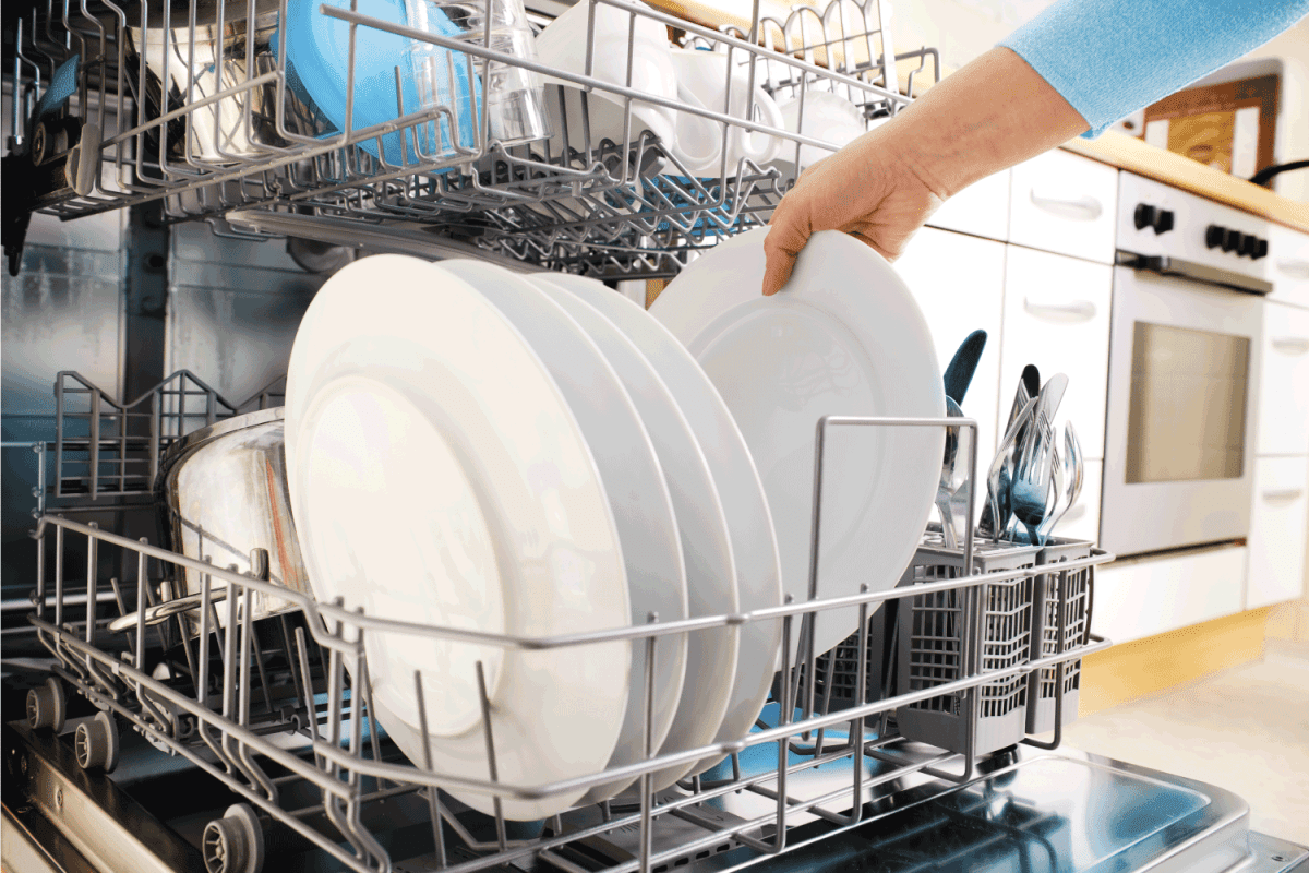 Hand getting clean plate from a dishwasher