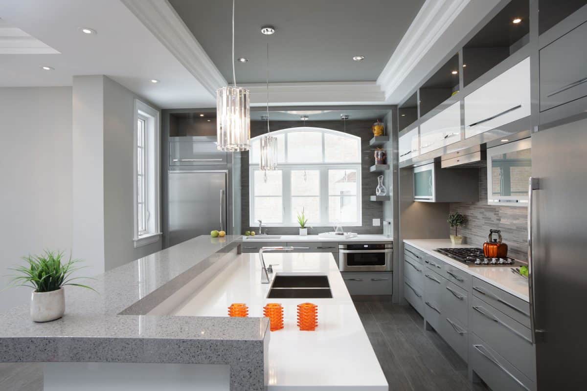 A luxurious and modern inspired kitchen with gray flooring, white countertops and gray cabinets and white cupboards