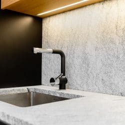 A modern and minimalist themed kitchen with stone marble countertop and black sink, Should Kitchen Sink Drain Match Faucet?