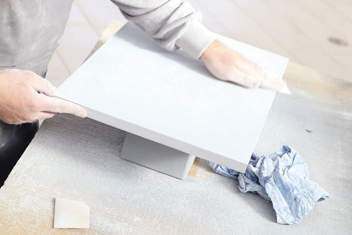 A painter using a sanding paper in smoothing the primer paint