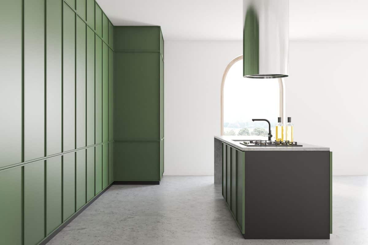 A spacious and green themed kitchen with a breakfast bar with a hood on top