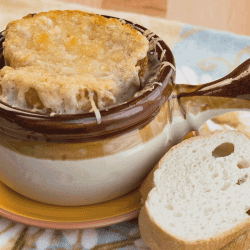 A traditional crock full of French Onion Soup topped with melted gruyere and served with fresh French bread. How To Cut Onions For French Onion Soup