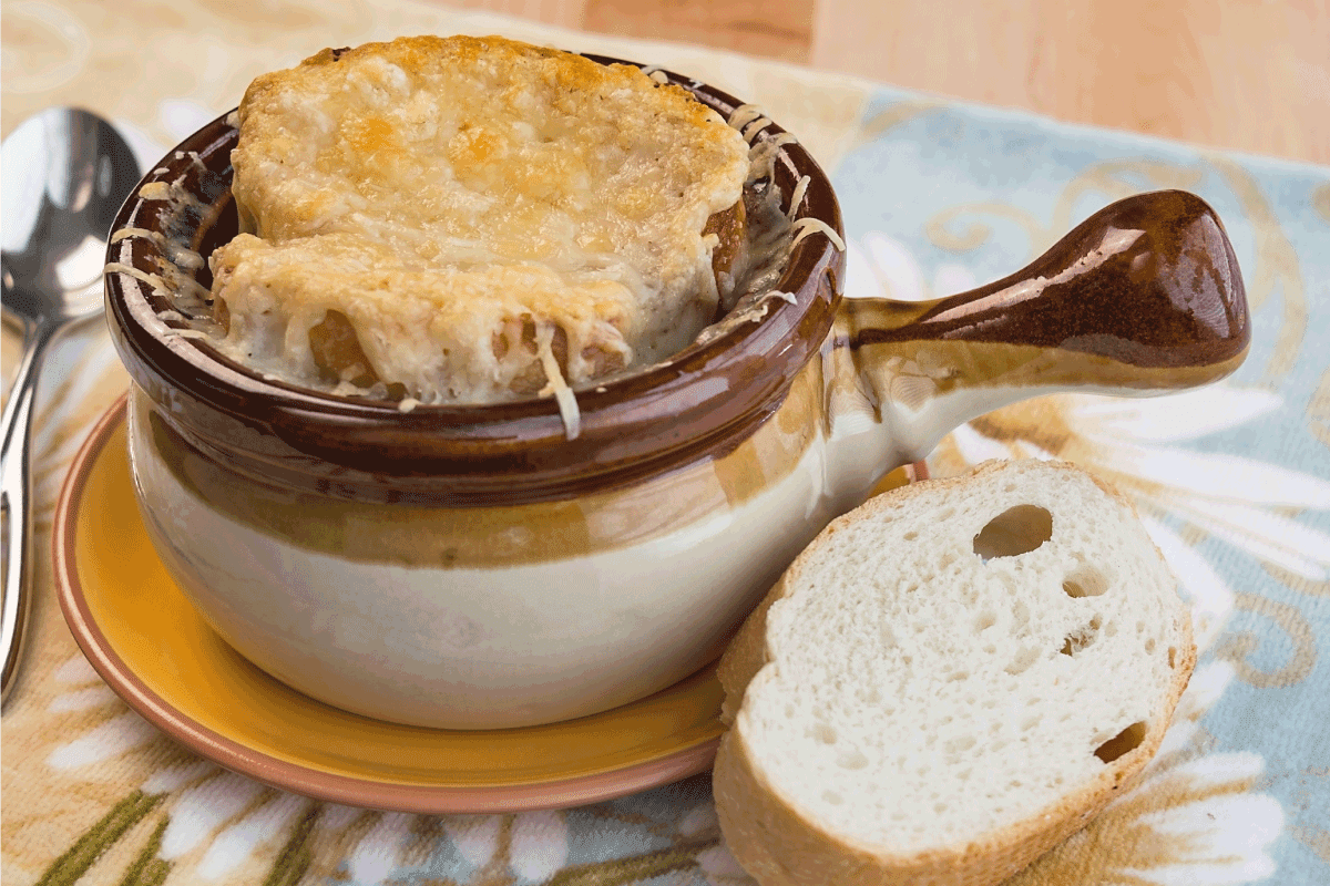 A traditional crock full of French Onion Soup topped with melted gruyere and served with fresh French bread. How To Cut Onions For French Onion Soup