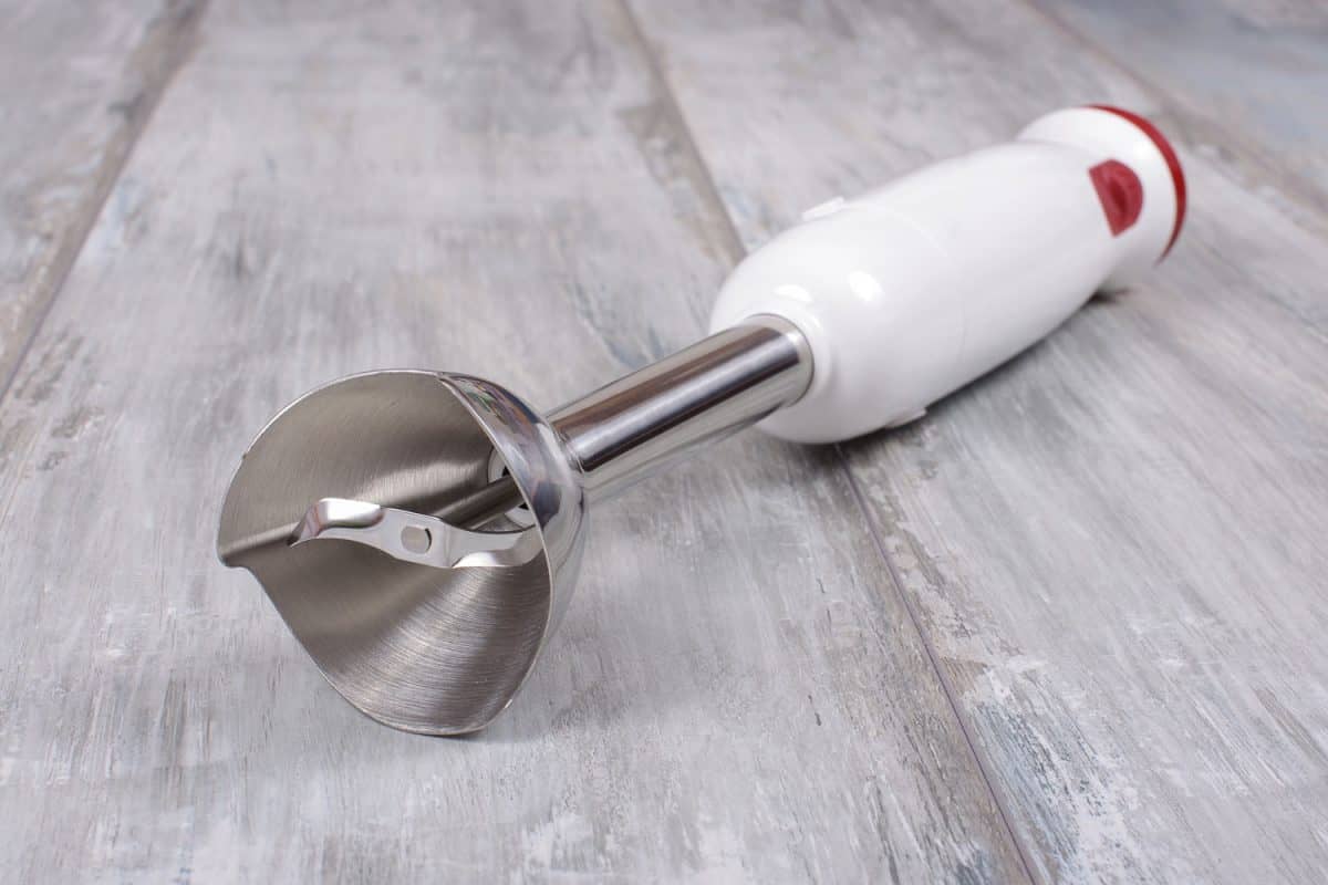 A white Immersion blender on top of a wooden table