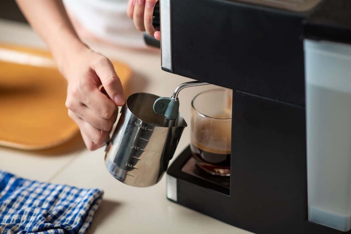A woman pouring steamed milk from the Espresso machine for a soothing cup of coffee
