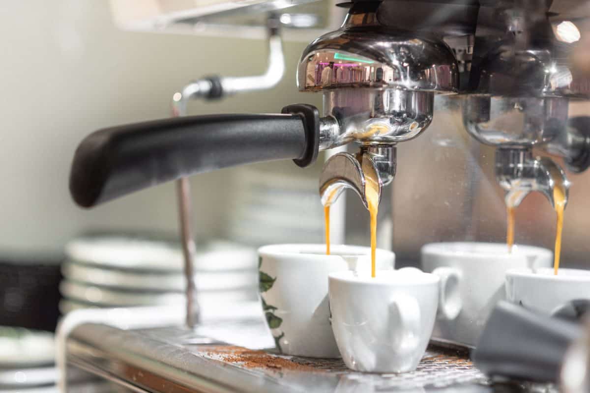 An espresso machine pouring two cups of coffee at the coffee shop