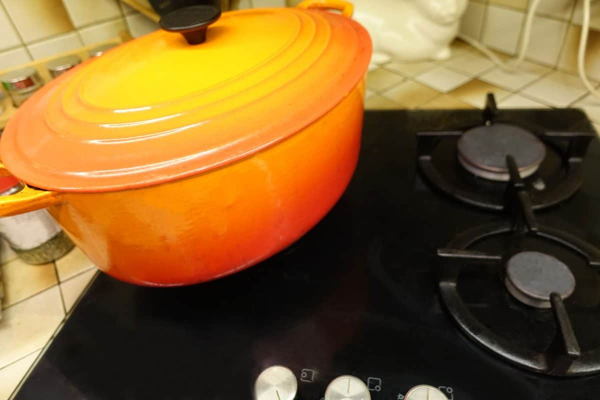 An orange Dutch oven on the cooktop
