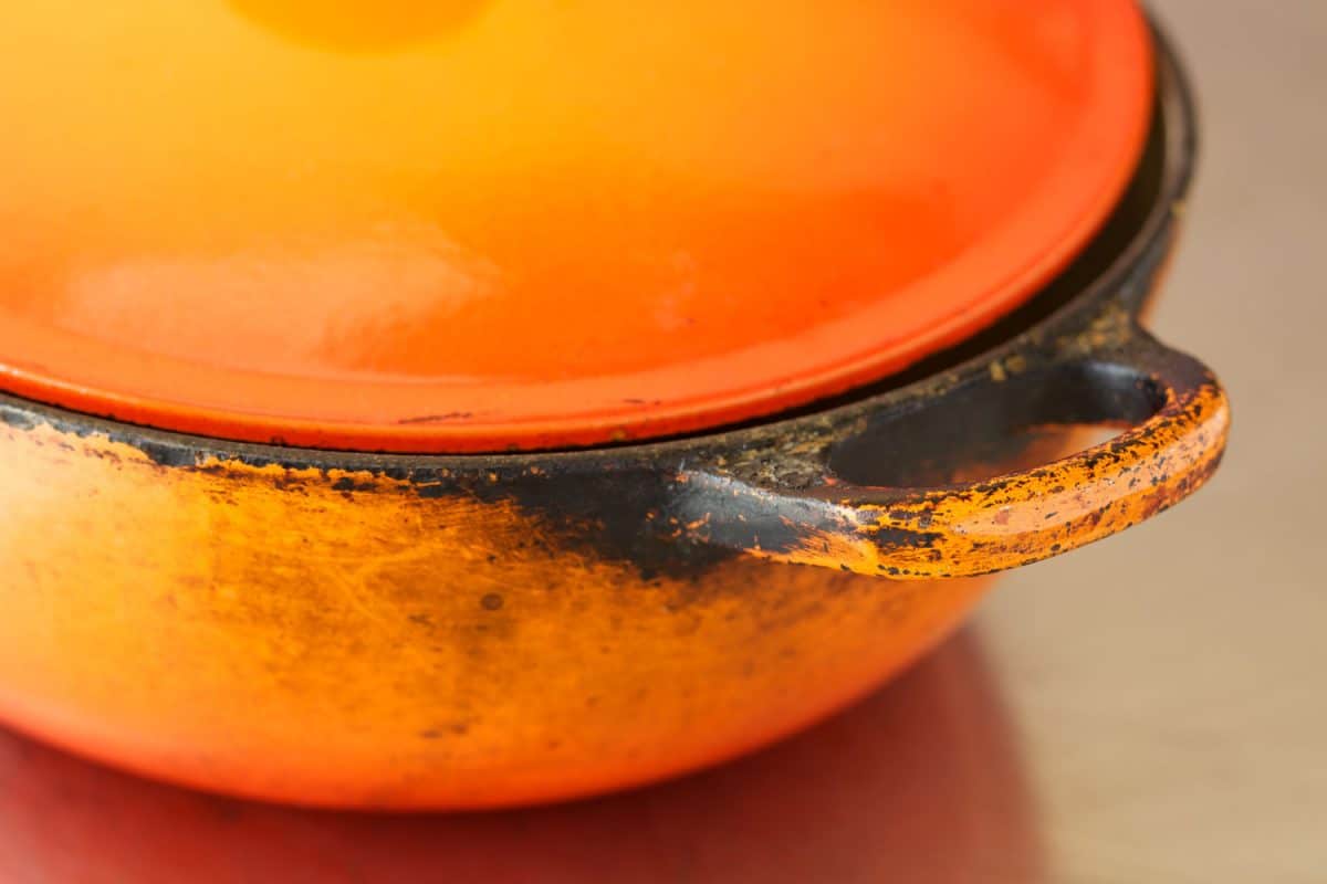 An orange Dutch oven with paint chipped away