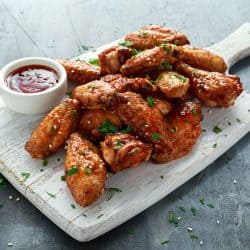 Chicken wings garnished with chives and ketchup dip on the side, Should You Marinate Wings Before Baking?