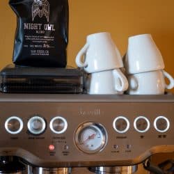 Cups and a bag of coffee beans placed on top of a Breville Espresso machine, How To Reset A Breville Espresso Machine