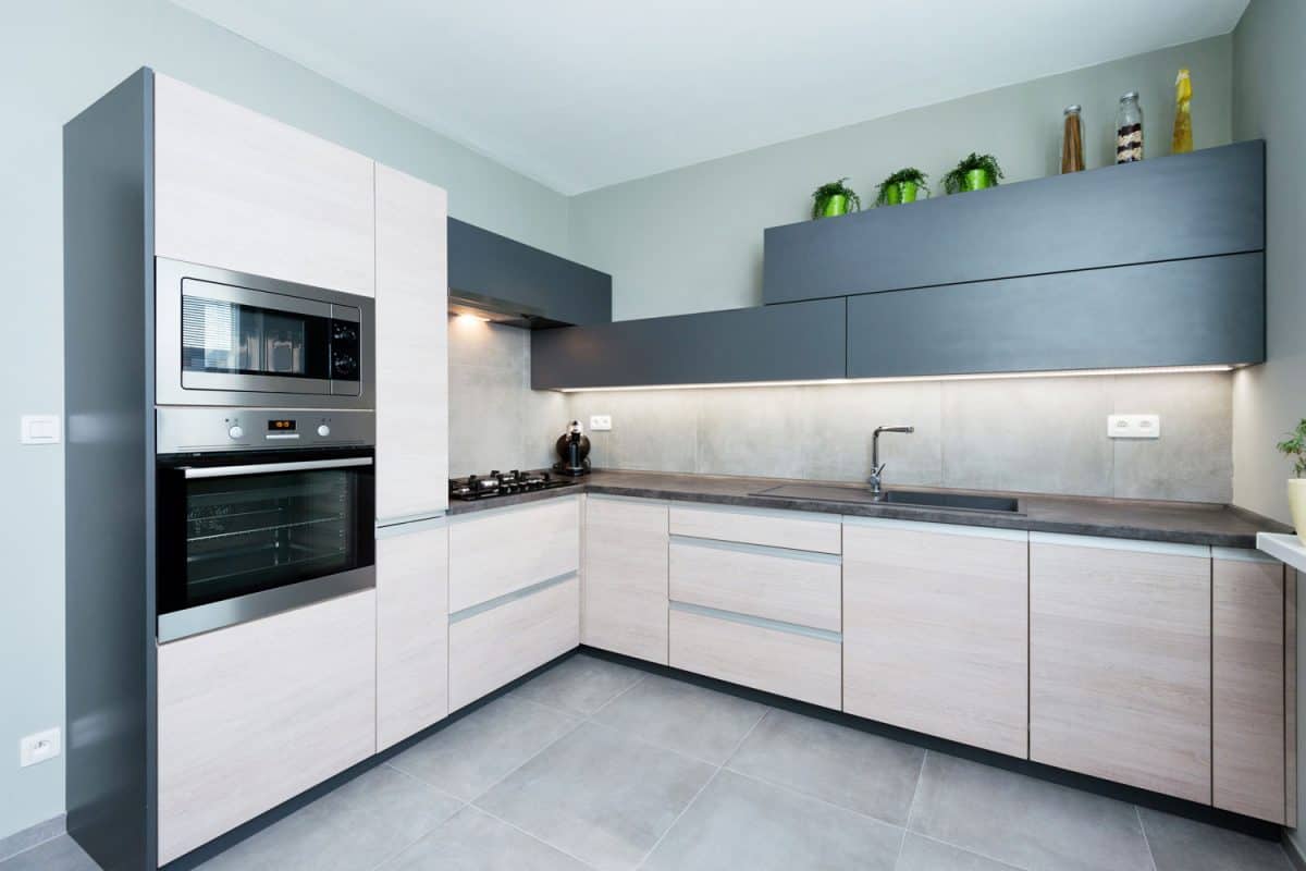 Luxurious and contemporary designed kitchen with black countertops and gray tiled flooring
