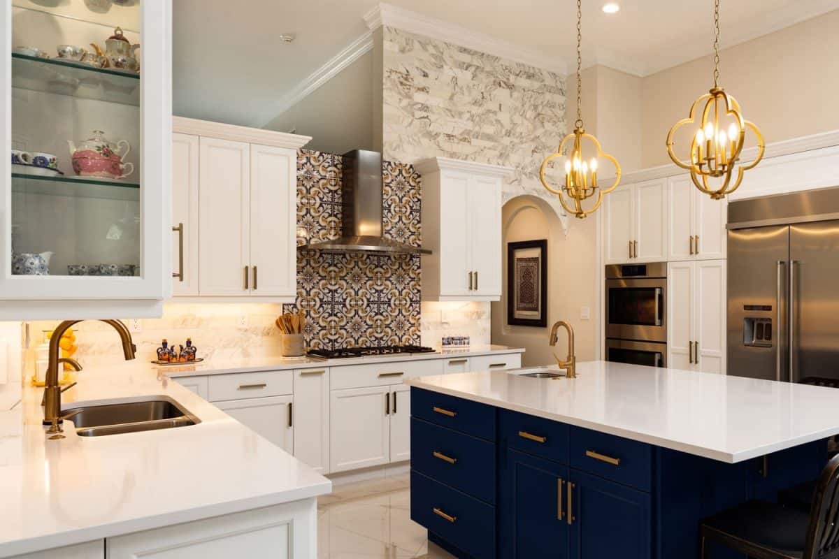 Luxurious modern designed kitchen with white kitchen countertop, white cabinets, and dark blue colored cabinets in the breakfast bar
