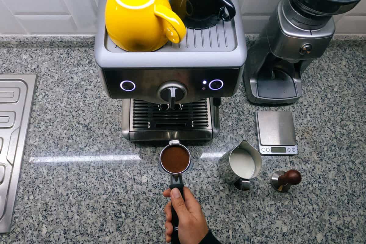 Man inserting newly ground coffee beans in the Espresso machine