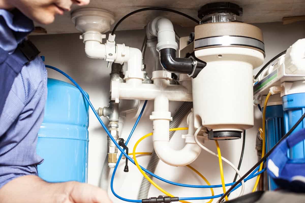 Plumber checking garbage disposal, How Many Amps Does A Garbage Disposal Draw? [By Horsepower]