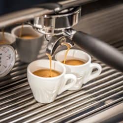 Professional espresso machine pouring fresh coffee into a ceramic cup, How Often Should You Descale An Espresso Machine?