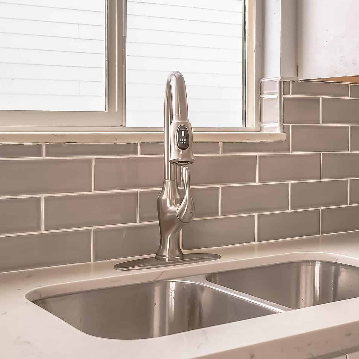 Square frame Undermount double bowl sink and faucet on the gleaming white kitchen countertop