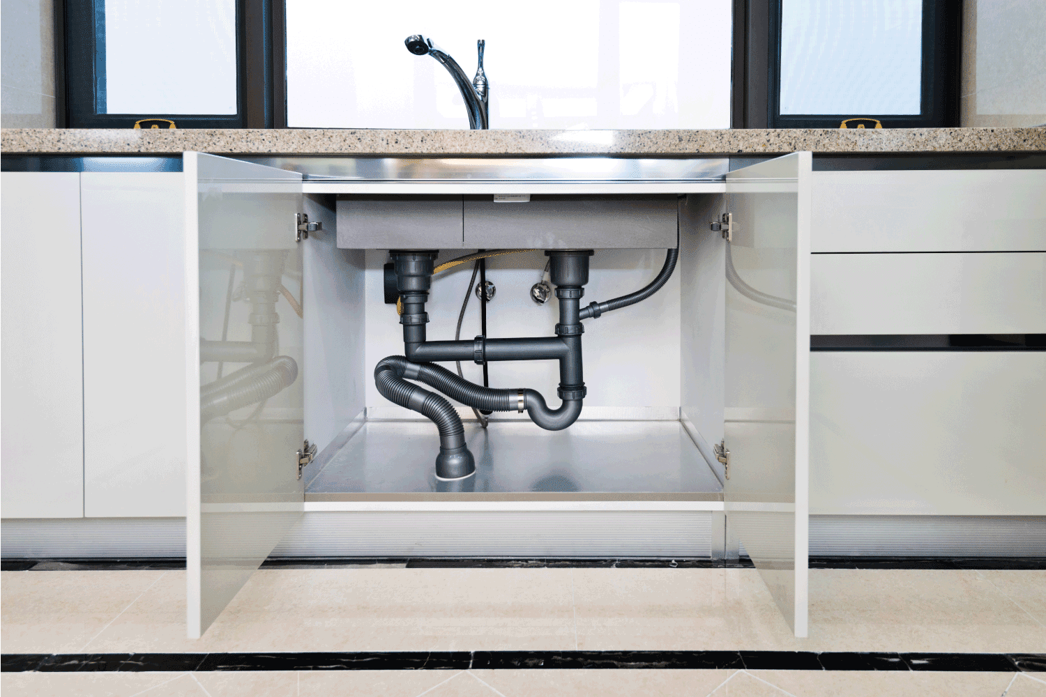 Water pipe under kitchen sink, open cabinet doors